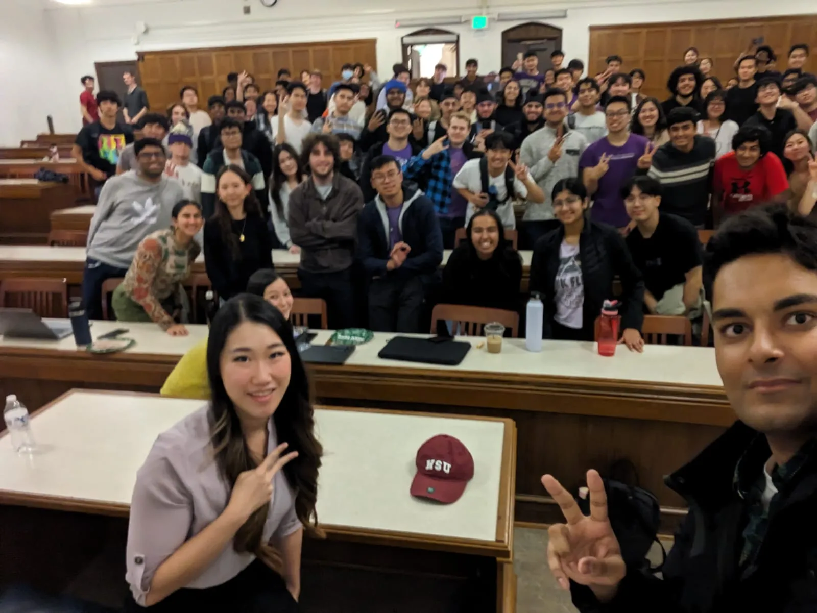 Selfie in a packed UW lecture hall, students smiling and throwing peace signs